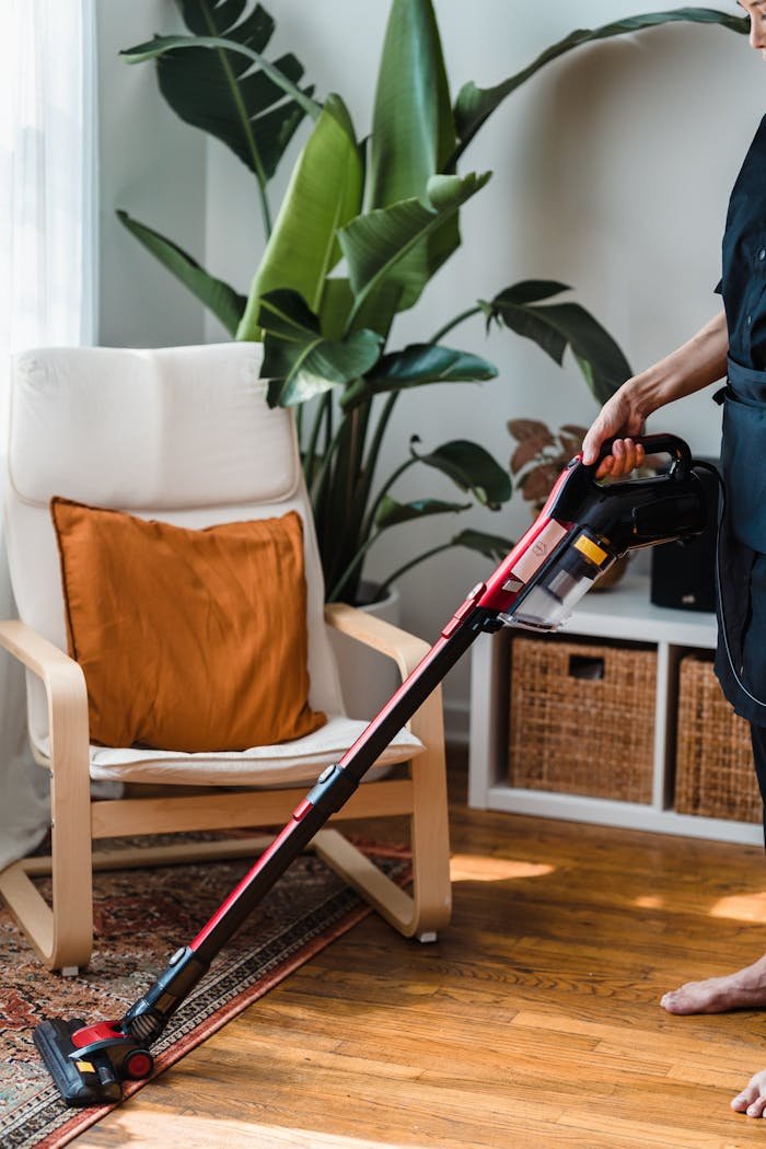 Person in Black T-shirt and Black Pants Holding Black and Red Vacuum Cleaner